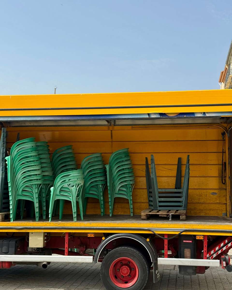 Camión de caja abierta cargado con sillas y mesas para un evento