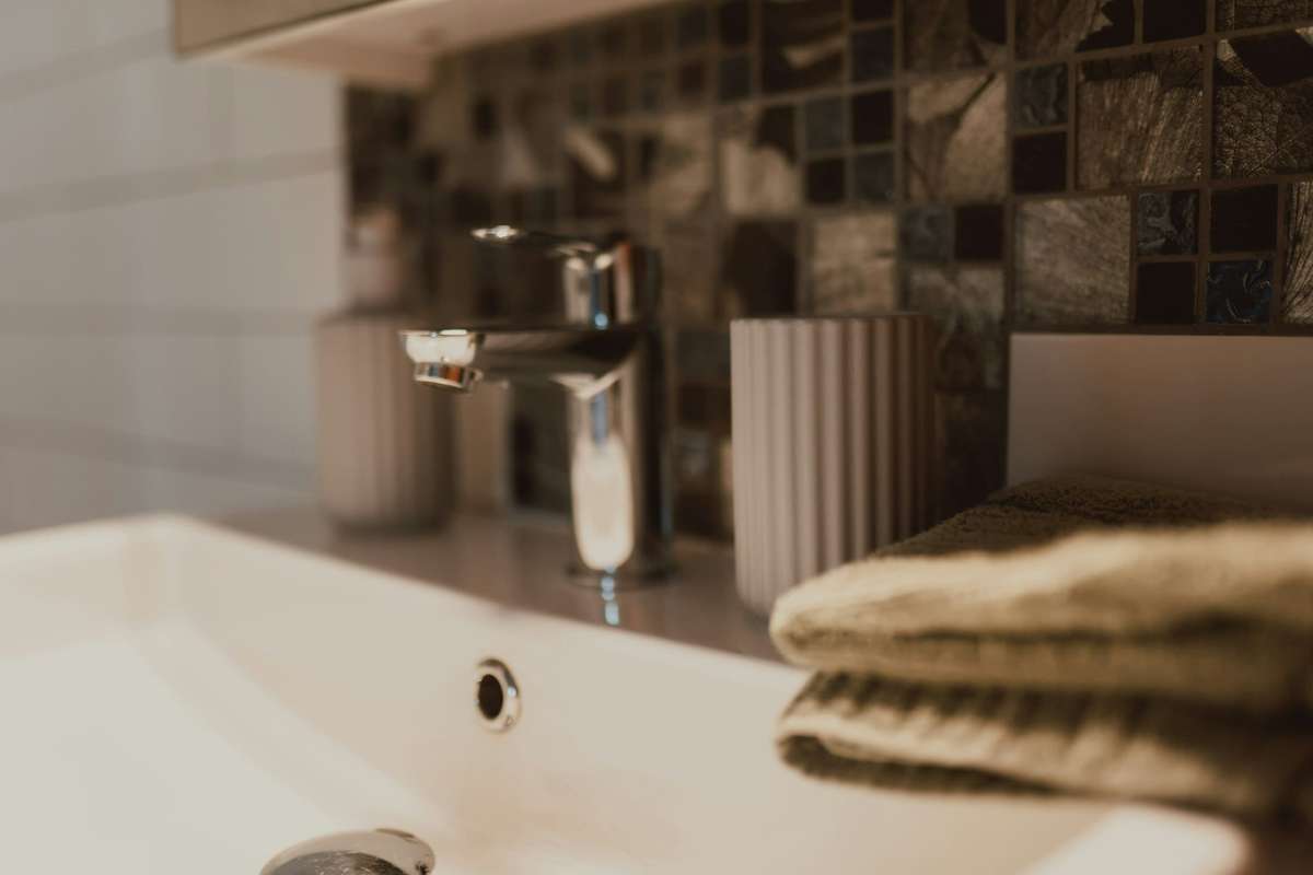 Lavabo blanco con grifo cromado y toallas dobladas de color arena
