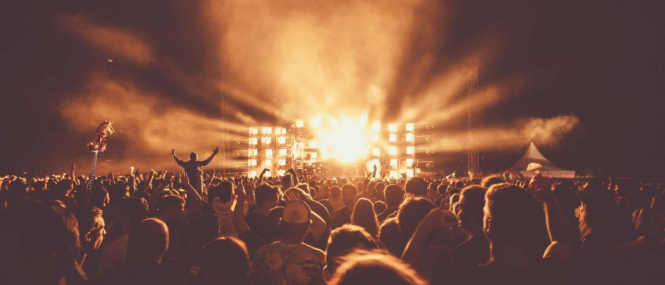 Público de un concierto al aire libre frente a un escenario iluminado con focos