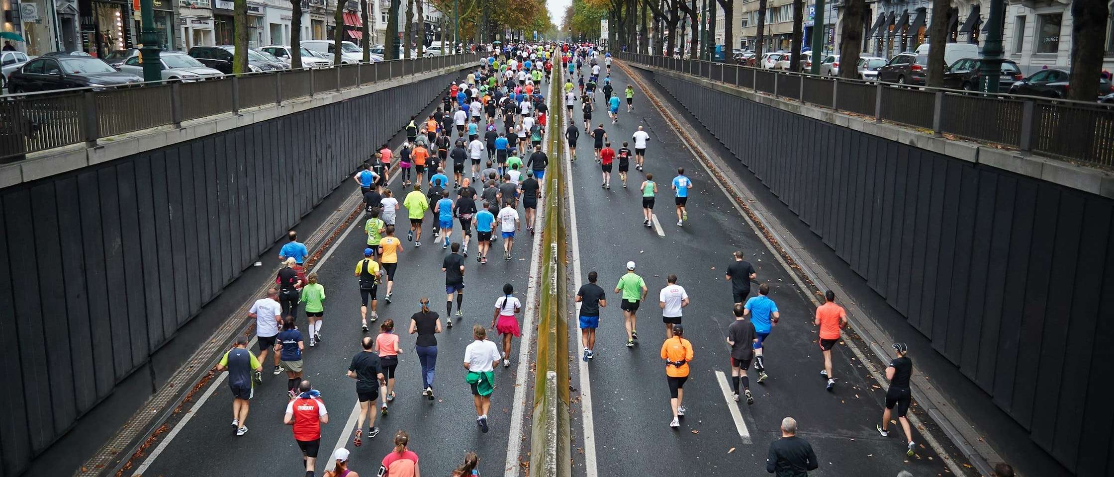 Corredores de un maratón vistos desde atrás en una avenida cortada al tráfico