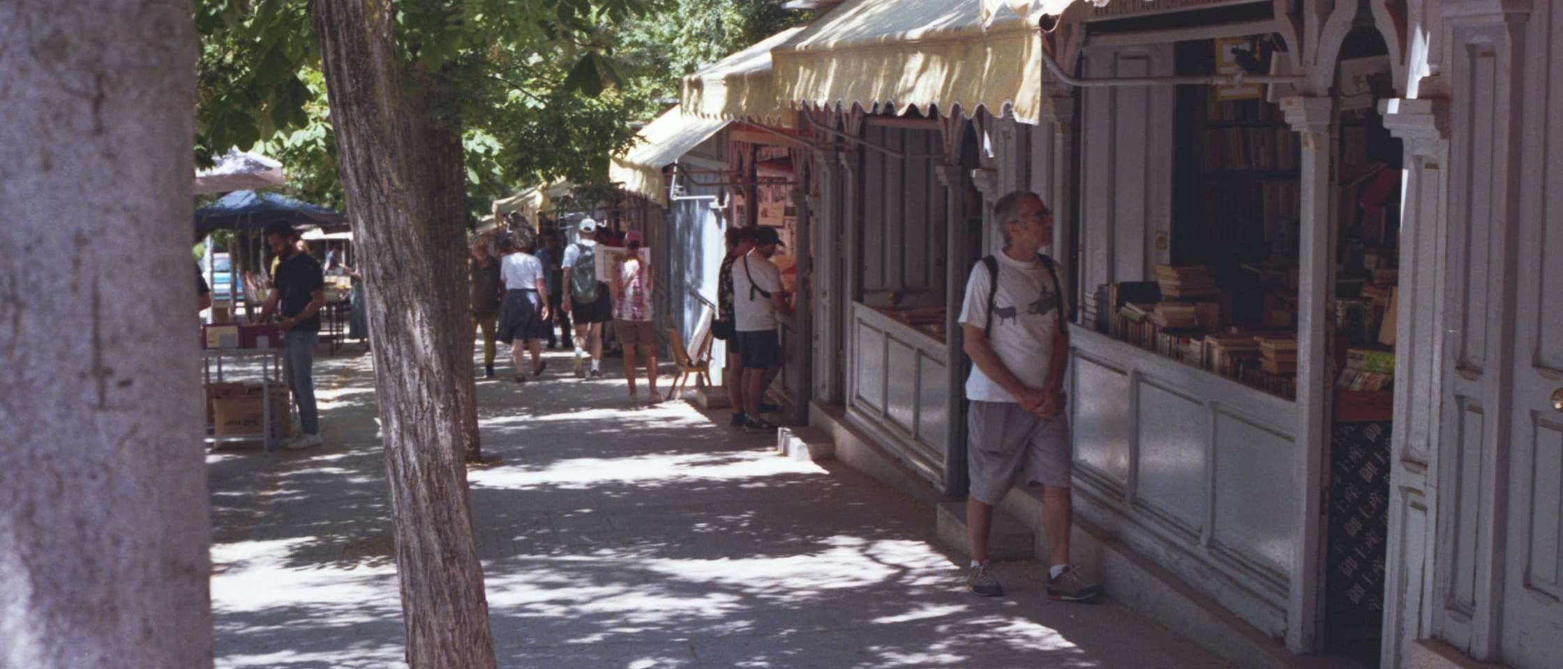 Casetas de madera de una feria al aire libre a lo largo de un paseo arbolado en Madrid