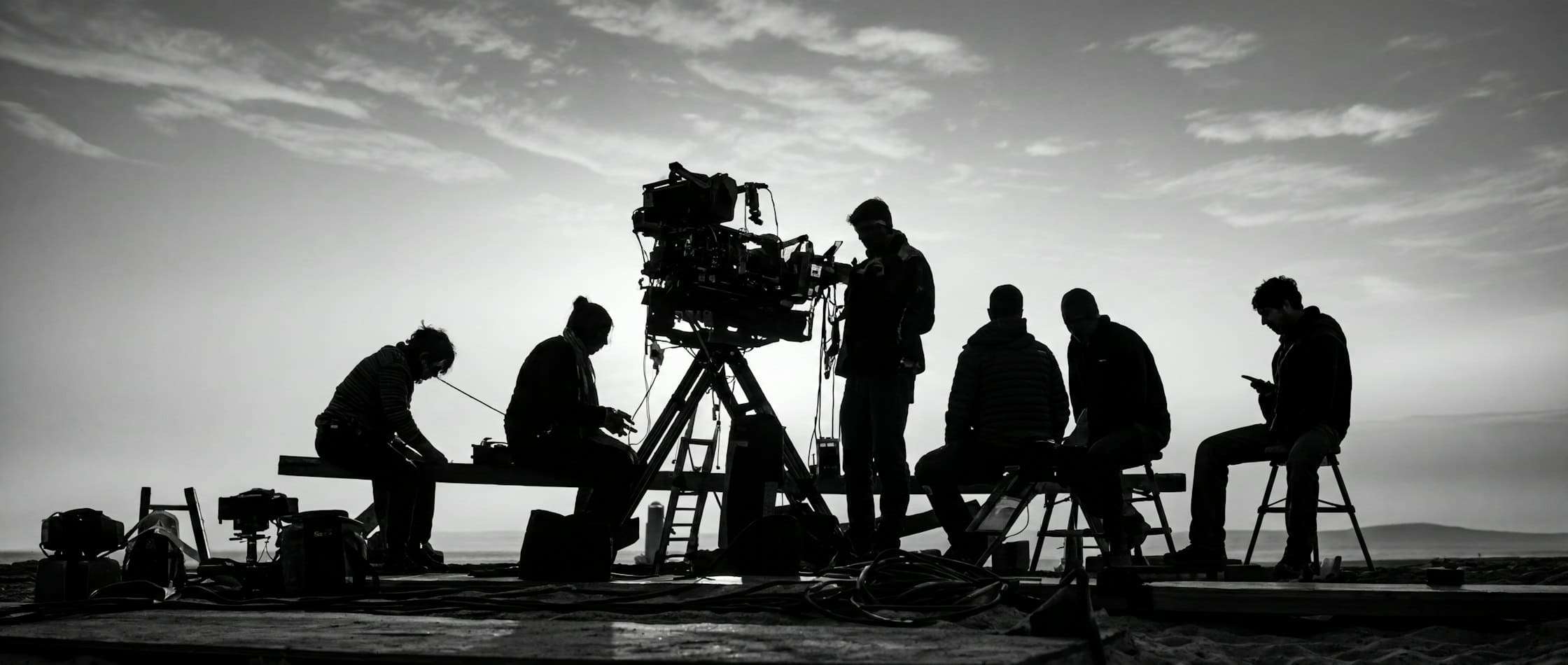 Equipo de rodaje con una cámara de cine sobre trípode en exteriores, en blanco y negro